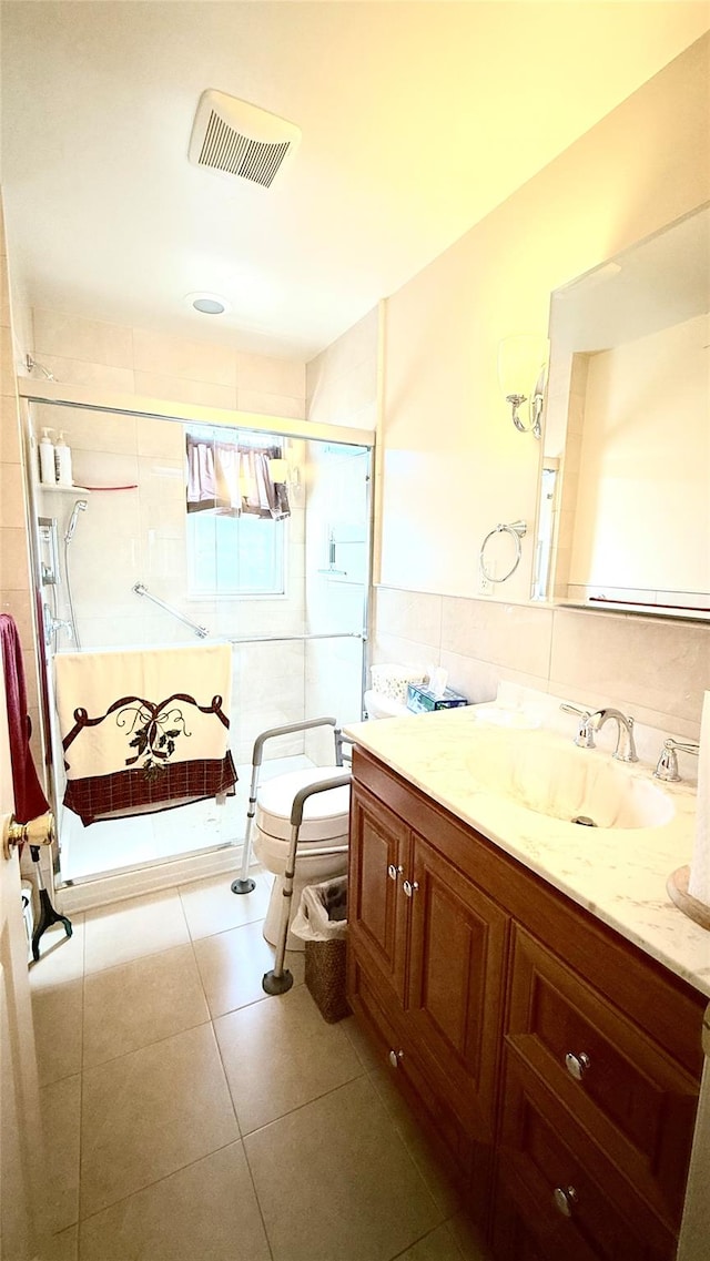 bathroom featuring visible vents, tile walls, a shower stall, tile patterned flooring, and vanity