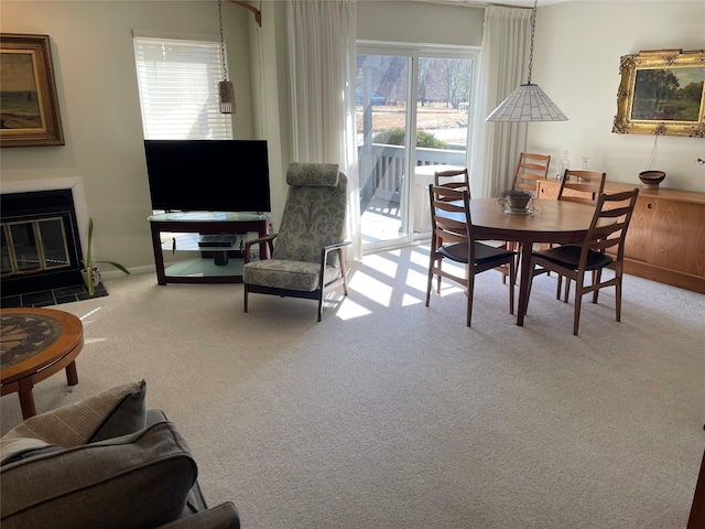 carpeted dining space with a fireplace with flush hearth and baseboards