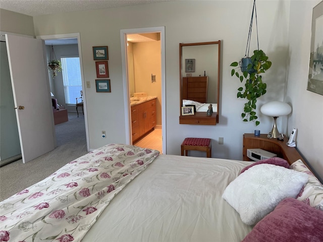 bedroom with light colored carpet, ensuite bath, and a textured ceiling