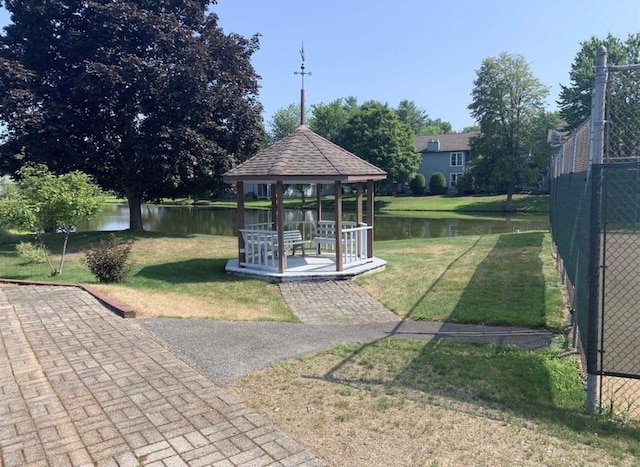 view of home's community with a gazebo, a water view, a yard, and fence