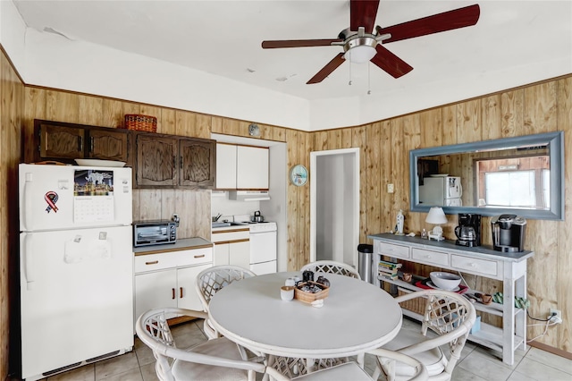 kitchen featuring light tile patterned floors, a toaster, wooden walls, and freestanding refrigerator