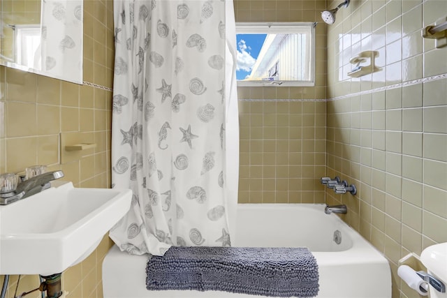 full bath with a sink, shower / bathtub combination with curtain, and tile walls