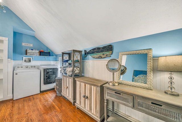 washroom featuring wood finished floors, wainscoting, and washing machine and clothes dryer