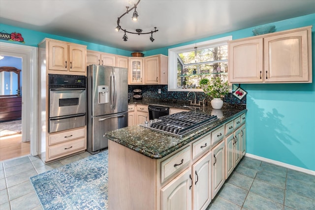 kitchen with dark stone countertops, a warming drawer, light brown cabinets, and stainless steel appliances