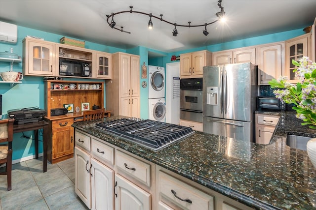 kitchen featuring stacked washer and clothes dryer, an AC wall unit, dark stone counters, appliances with stainless steel finishes, and glass insert cabinets