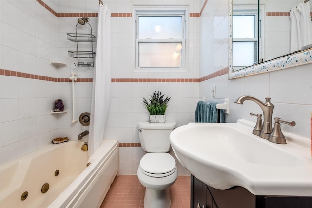 bathroom featuring a combined bath / shower with jetted tub, a sink, tile walls, toilet, and tile patterned floors