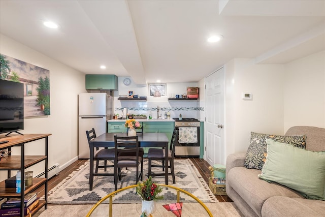 dining space featuring recessed lighting, a baseboard radiator, baseboards, and wood finished floors