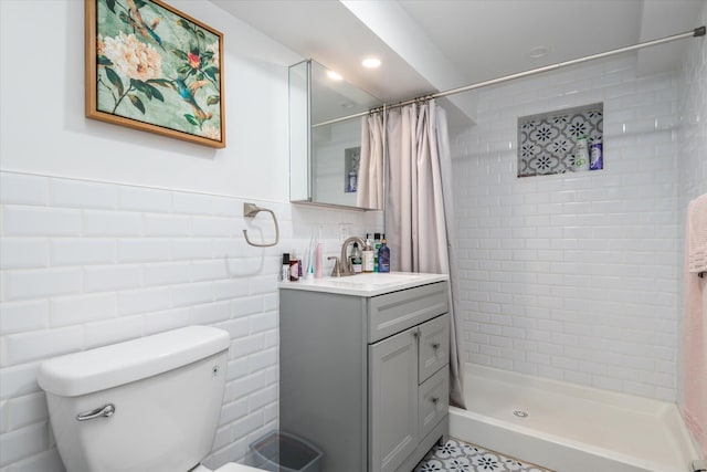 bathroom featuring toilet, tile walls, a stall shower, and vanity