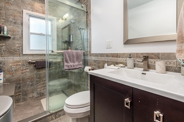 bathroom featuring toilet, tile walls, a stall shower, and vanity