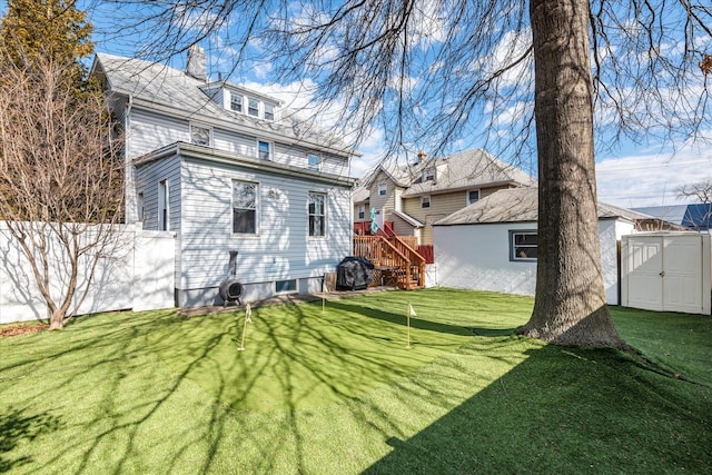 rear view of property featuring an outbuilding, fence, a chimney, a storage shed, and a lawn