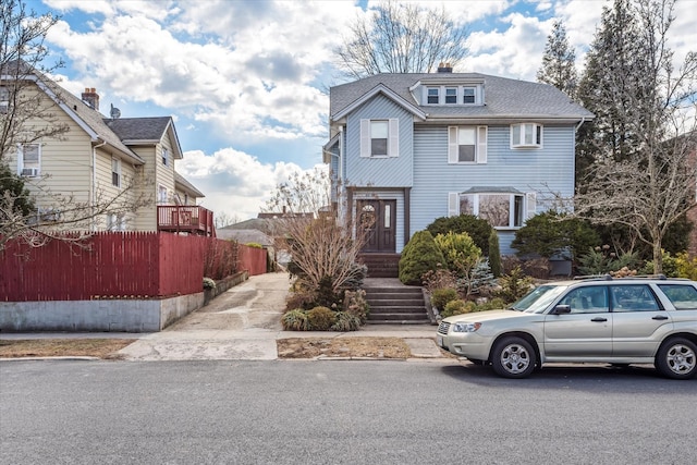 american foursquare style home with roof with shingles and fence