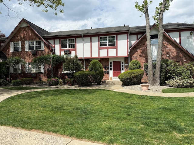 tudor house with a front yard, stucco siding, and brick siding