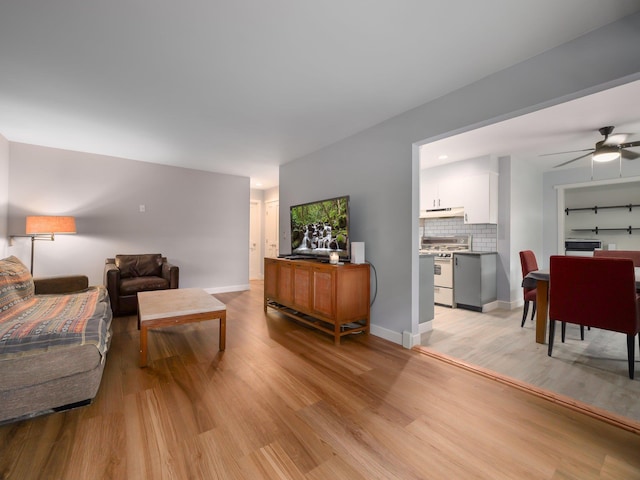 living room featuring light wood finished floors, ceiling fan, and baseboards
