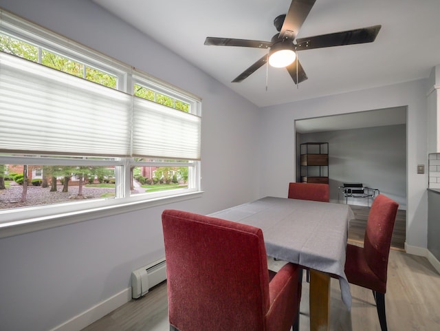 dining room with a baseboard heating unit, light wood-type flooring, baseboards, and a ceiling fan