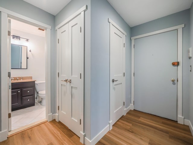 hallway with light wood finished floors and a sink