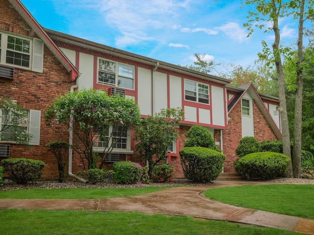 view of front of house featuring stucco siding, a front lawn, and brick siding