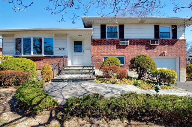 split level home with an attached garage and brick siding