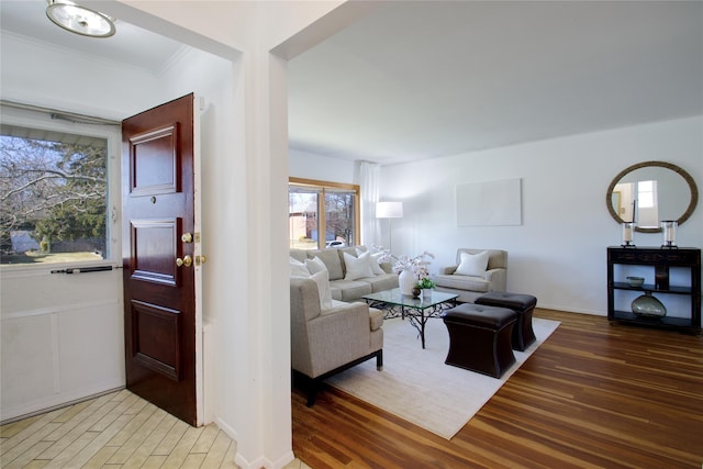 living area with baseboards, light wood-style floors, and ornamental molding