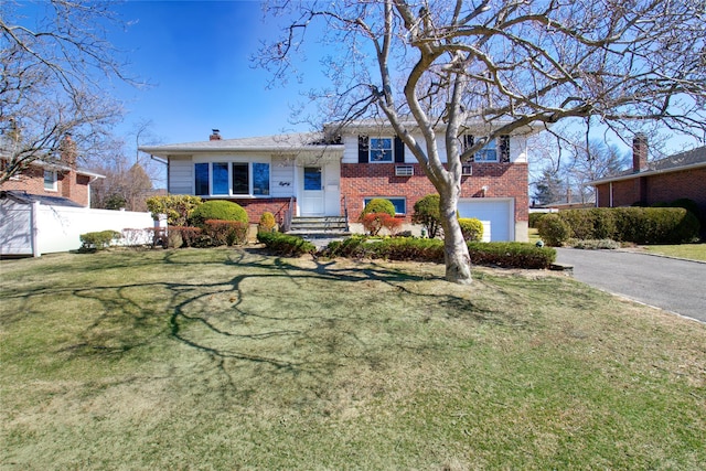 split level home featuring a front yard, fence, driveway, entry steps, and brick siding