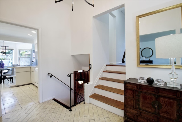 staircase with tile patterned floors, a notable chandelier, and recessed lighting