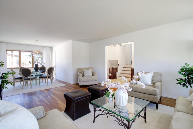 living room featuring stairway, baseboards, a notable chandelier, and wood finished floors