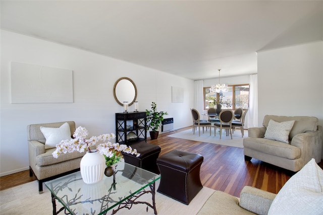 living room with baseboards, a notable chandelier, and wood finished floors