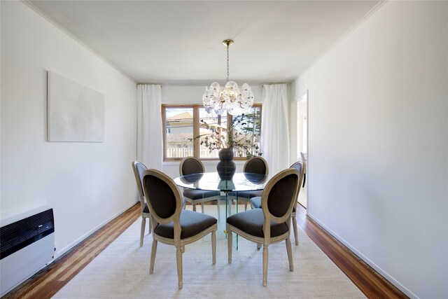 dining area with heating unit, wood finished floors, baseboards, crown molding, and a chandelier