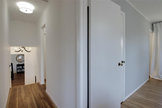 hall featuring an upstairs landing, crown molding, baseboards, and wood finished floors