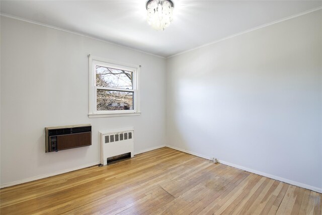 unfurnished room featuring light wood-type flooring, ornamental molding, heating unit, radiator heating unit, and baseboards