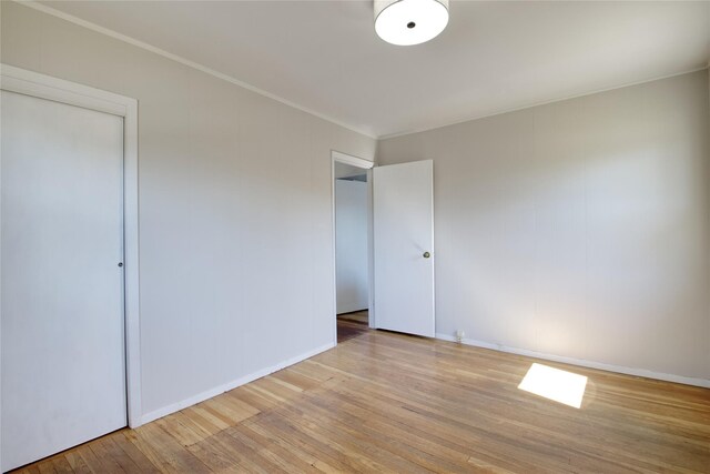 unfurnished bedroom with crown molding, baseboards, and wood finished floors