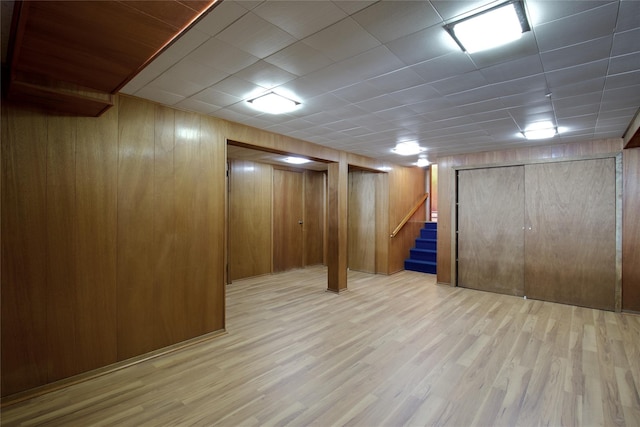 finished basement featuring stairway, wooden walls, and wood finished floors