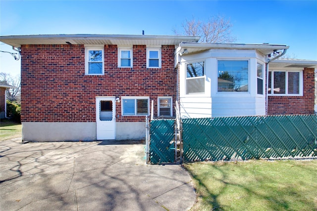 view of front of home with a gate, brick siding, and fence