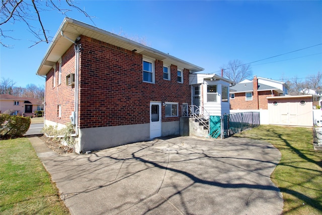 back of house with a storage shed, an outbuilding, a yard, and brick siding