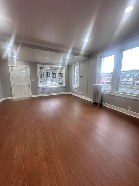 unfurnished living room with baseboards, radiator, and dark wood-style flooring