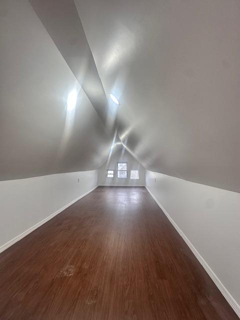 additional living space with vaulted ceiling, baseboards, and wood finished floors