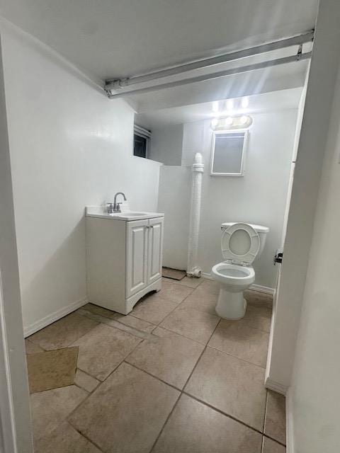 bathroom with tile patterned flooring, toilet, vanity, and baseboards