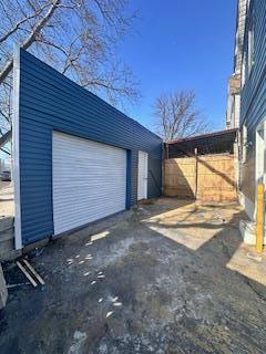 detached garage featuring driveway and fence