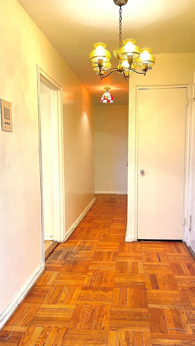 hall featuring a notable chandelier and baseboards