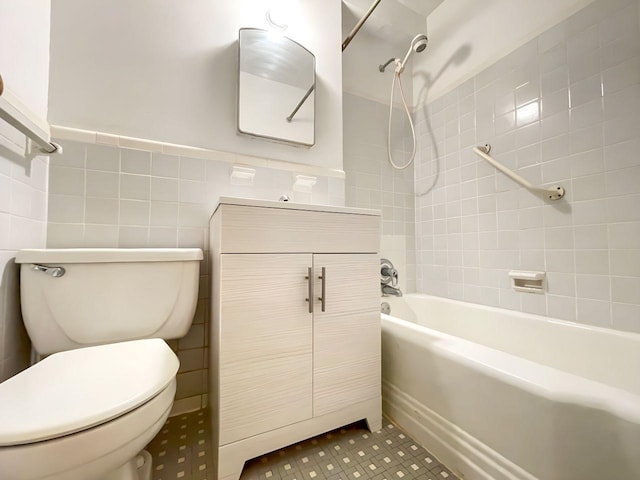 bathroom featuring a wainscoted wall, toilet, tile walls, washtub / shower combination, and vanity