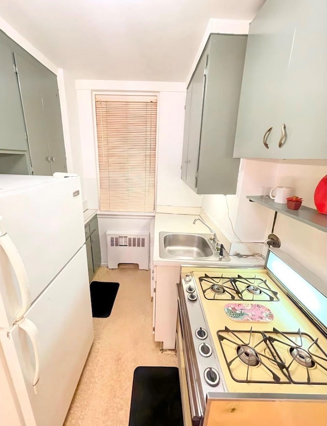 kitchen with range with gas stovetop, radiator heating unit, freestanding refrigerator, gray cabinetry, and a sink