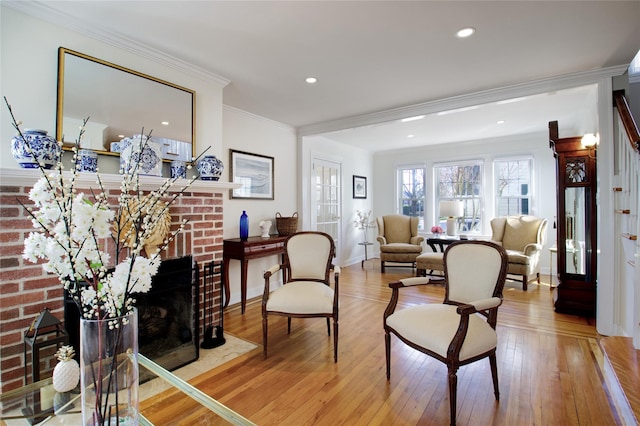 living area with recessed lighting, ornamental molding, a fireplace, and wood-type flooring