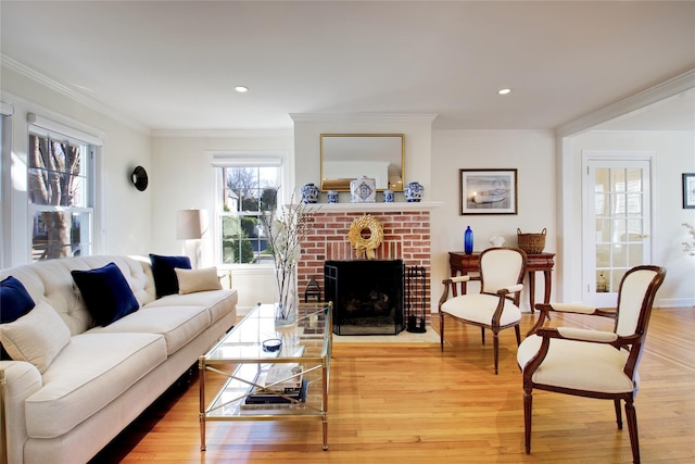 living room featuring recessed lighting, light wood-style floors, a fireplace, and crown molding