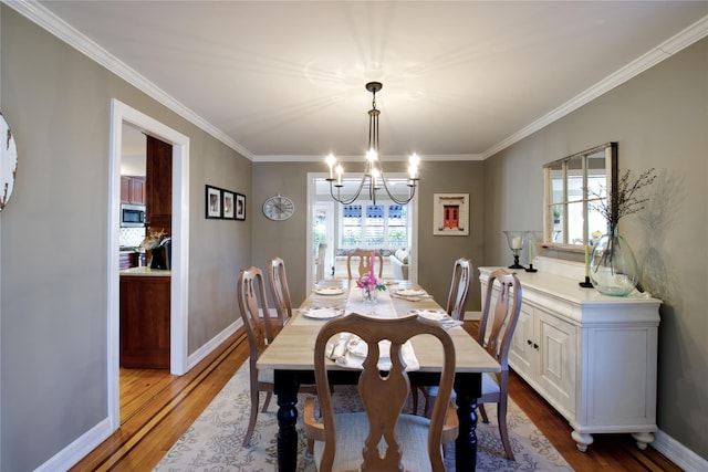 dining area with plenty of natural light, baseboards, an inviting chandelier, and wood finished floors