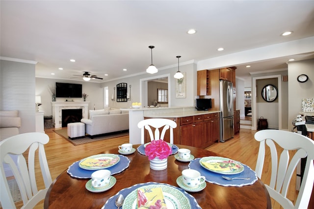 dining room with a fireplace, light wood-type flooring, and crown molding