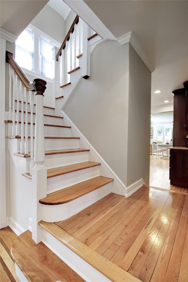 stairway with hardwood / wood-style floors, crown molding, recessed lighting, and baseboards