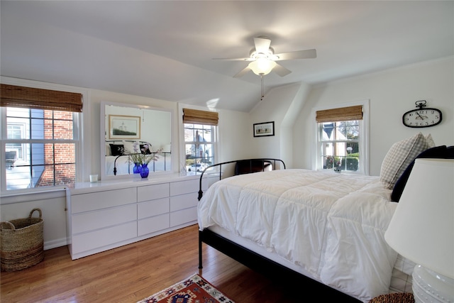 bedroom featuring multiple windows, ceiling fan, vaulted ceiling, and light wood finished floors