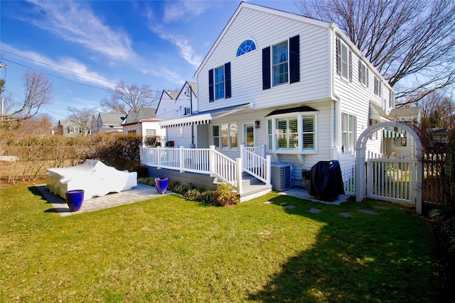 view of front of house featuring central AC unit, a deck, a front yard, and a gate