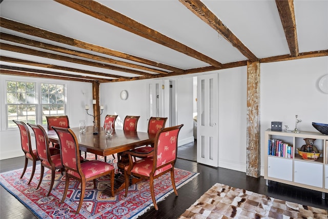 dining room featuring beam ceiling, wood finished floors, and baseboards
