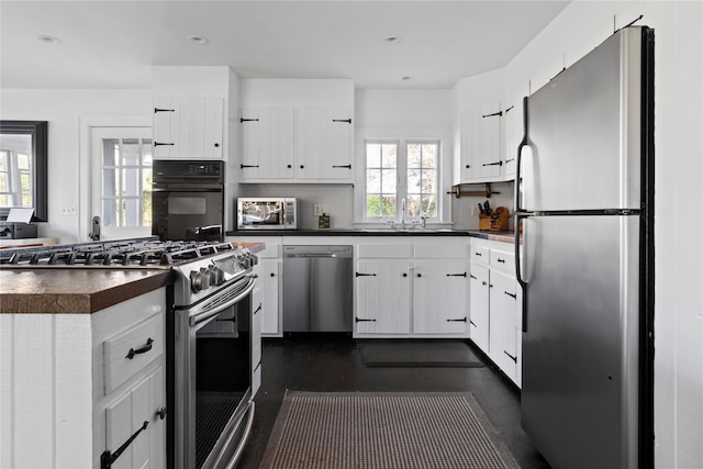 kitchen with recessed lighting, a sink, white cabinets, appliances with stainless steel finishes, and dark countertops