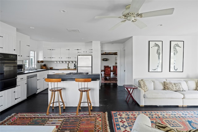 kitchen with dark countertops, black oven, dishwasher, freestanding refrigerator, and a warming drawer